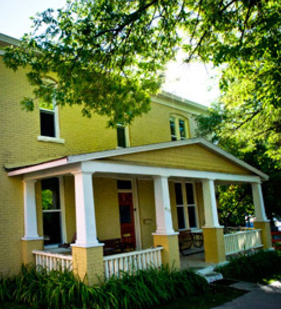 Yellow house with green trees and porch